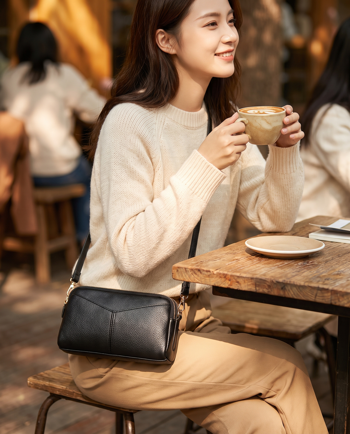 Woman at an outdoor cafe wearing the Capri bag crossbody